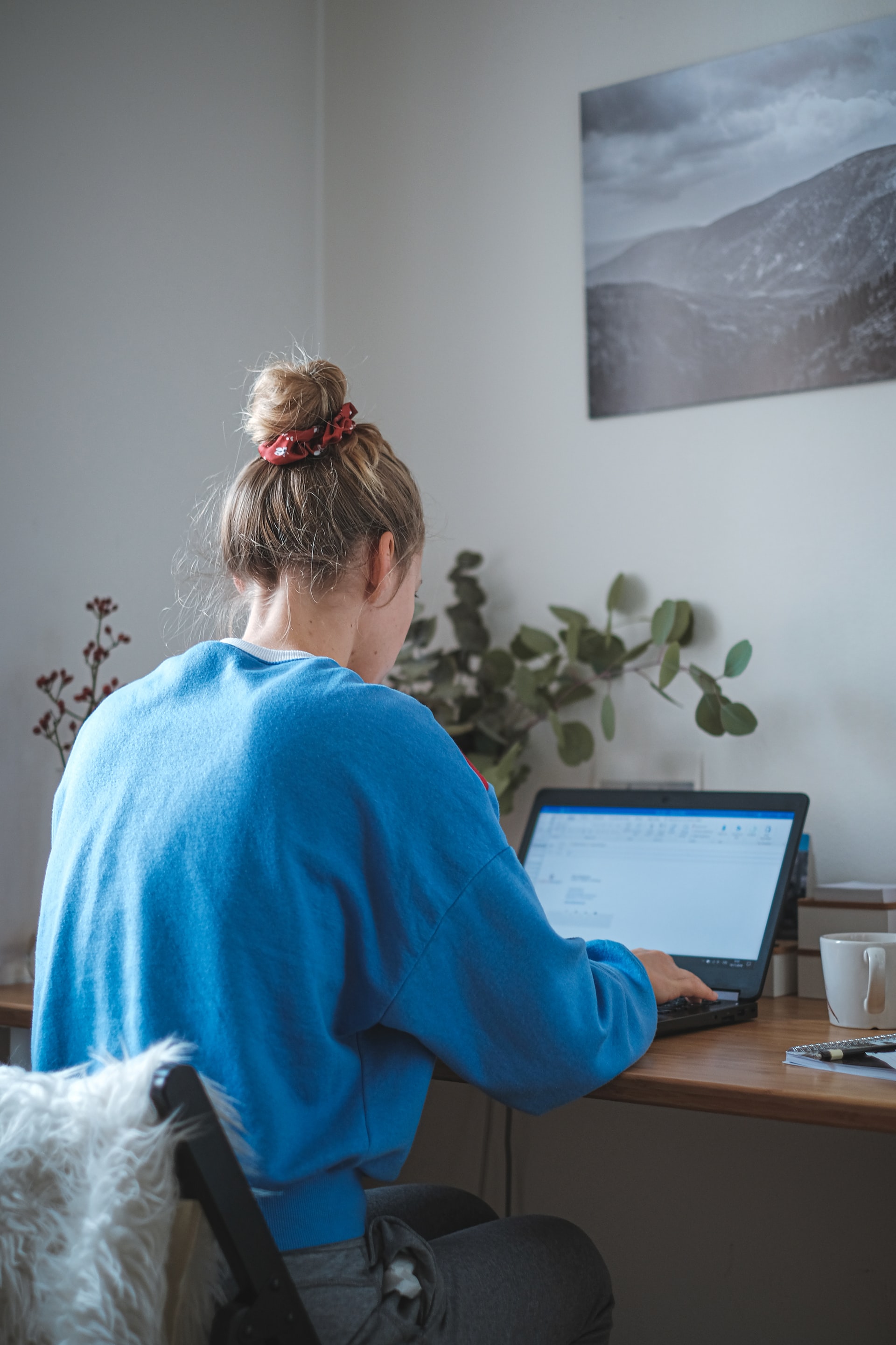 woman in blue sweater sitting in front of computer